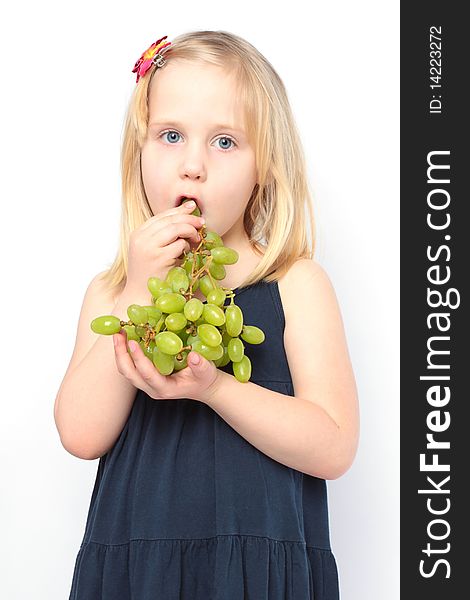 Beautiful girl in blue dress eats green grapes. Series - family with fruits and vegetables. Beautiful girl in blue dress eats green grapes. Series - family with fruits and vegetables