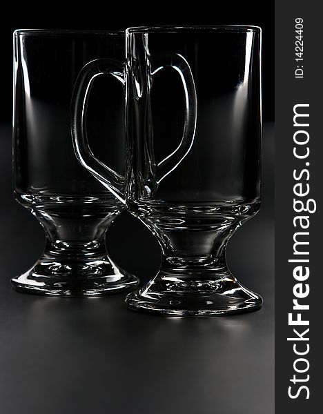 Two empty transparent glass cup on a dark background. Two empty transparent glass cup on a dark background