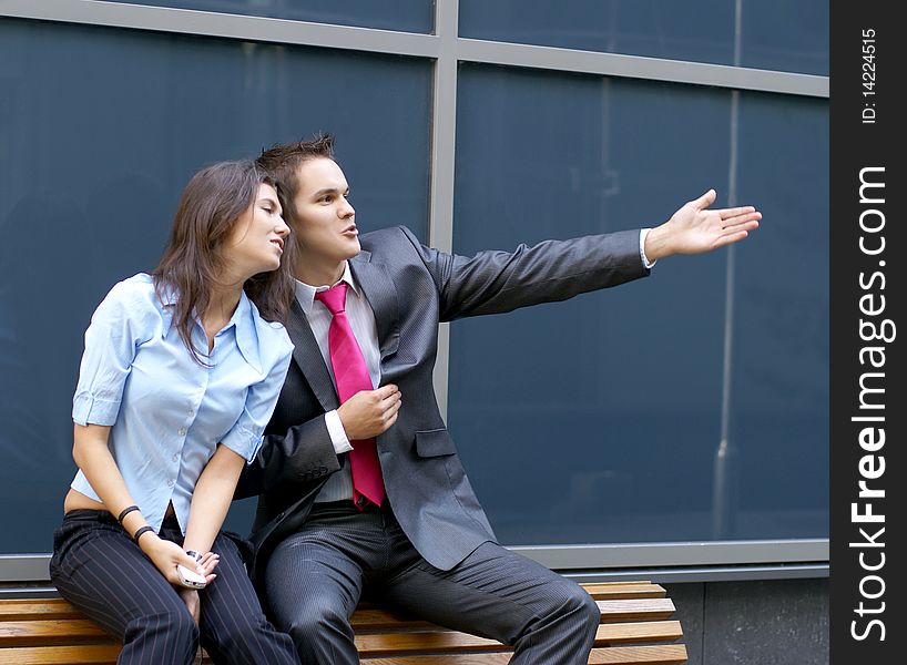 A young business couple sitting on a bench