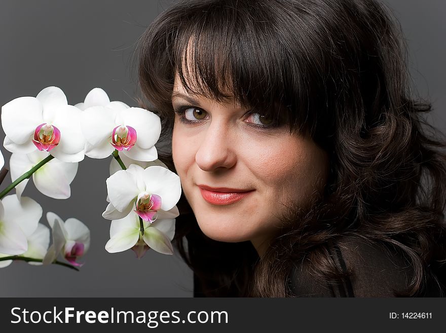 Young curly girl with white phalaenopsis on gray background. Young curly girl with white phalaenopsis on gray background