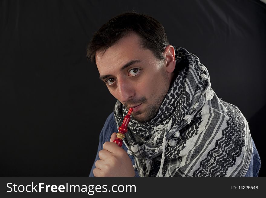 Young man enjoying hookah on a black background. Young man enjoying hookah on a black background