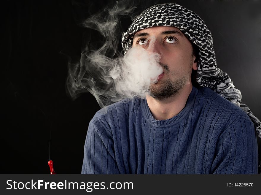 Young man enjoying hookah on a black background. Young man enjoying hookah on a black background