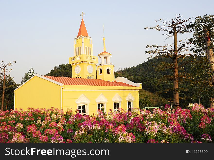 A yellow church.In the garden.Colorful.with tree and flower.