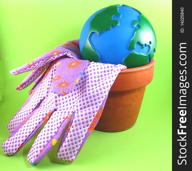 Globe in a flower pot with gardening gloves. Globe in a flower pot with gardening gloves