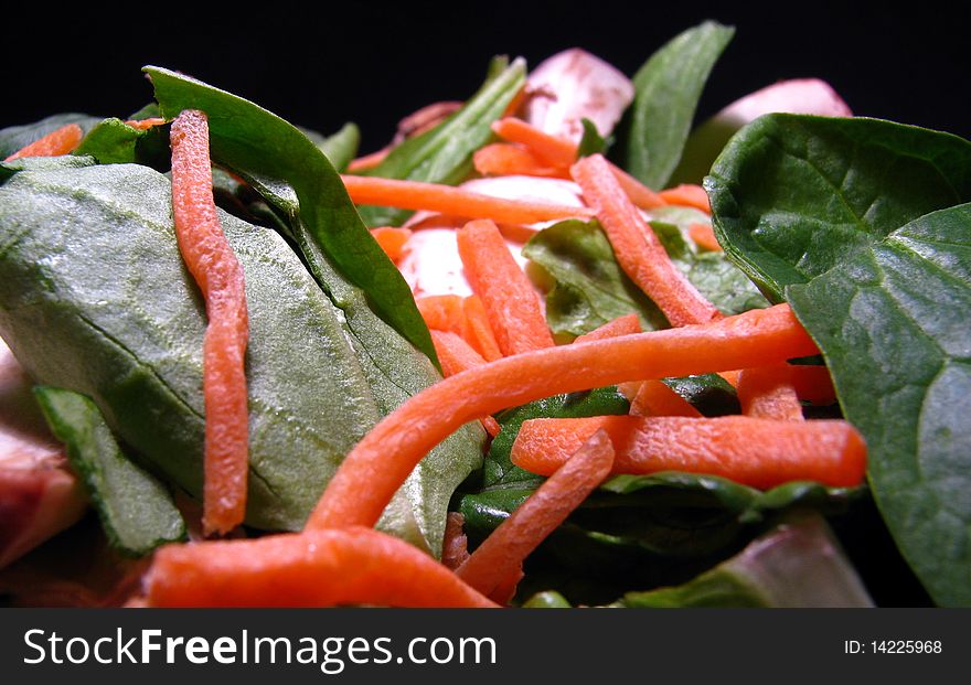 A fresh spinach, mushroom, carrot salad on black background. A fresh spinach, mushroom, carrot salad on black background