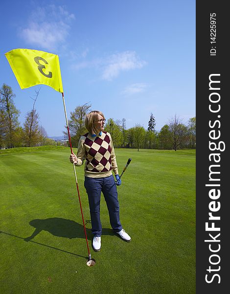 Woman holding a yellow flag number three on a golf course. Woman holding a yellow flag number three on a golf course.