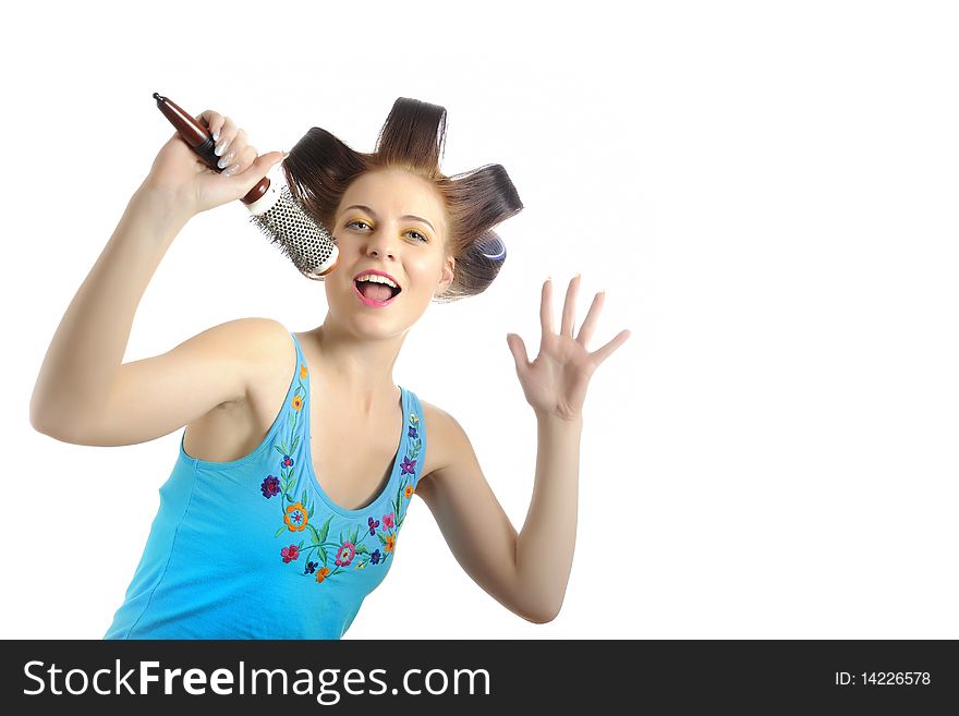 Young beautiful woman singing to the brush microphone while getting her hairstyle done with curlers on her hair. isolated on white background. copy-space. Young beautiful woman singing to the brush microphone while getting her hairstyle done with curlers on her hair. isolated on white background. copy-space