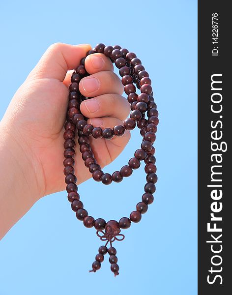 Prayer beads in her hands.Against the background of blue sky.