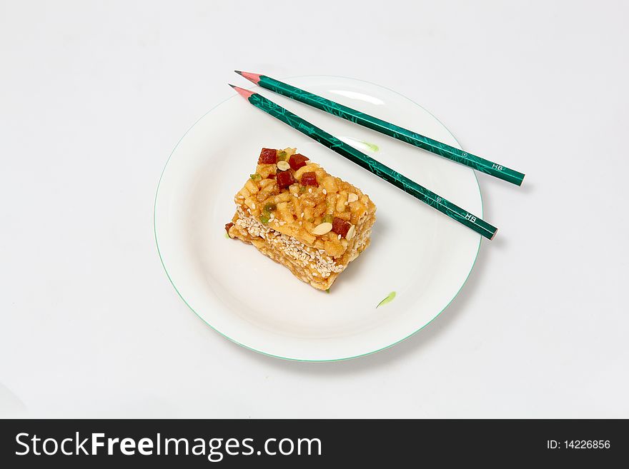 Piece of cake isolated on withe plate with two pencils. Piece of cake isolated on withe plate with two pencils