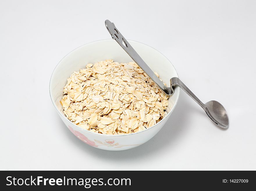 Bowl full of Oat and a spoon on white background. Bowl full of Oat and a spoon on white background