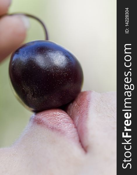 Close up view of a woman trying to eat a cherry. Close up view of a woman trying to eat a cherry.