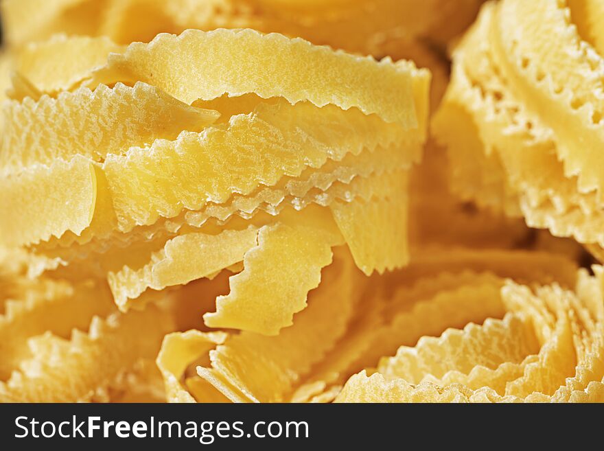 Beautiful nest of  fettuccine pasta  close up , thin ribbons of pasta with geometrical edges and rough surface. Beautiful nest of  fettuccine pasta  close up , thin ribbons of pasta with geometrical edges and rough surface