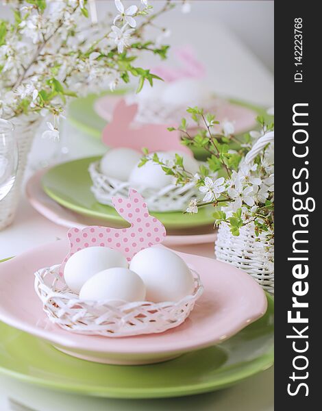 Happy easter. Decor and table setting of the Easter table is a vase with pink tulips and dishes of pink and green color