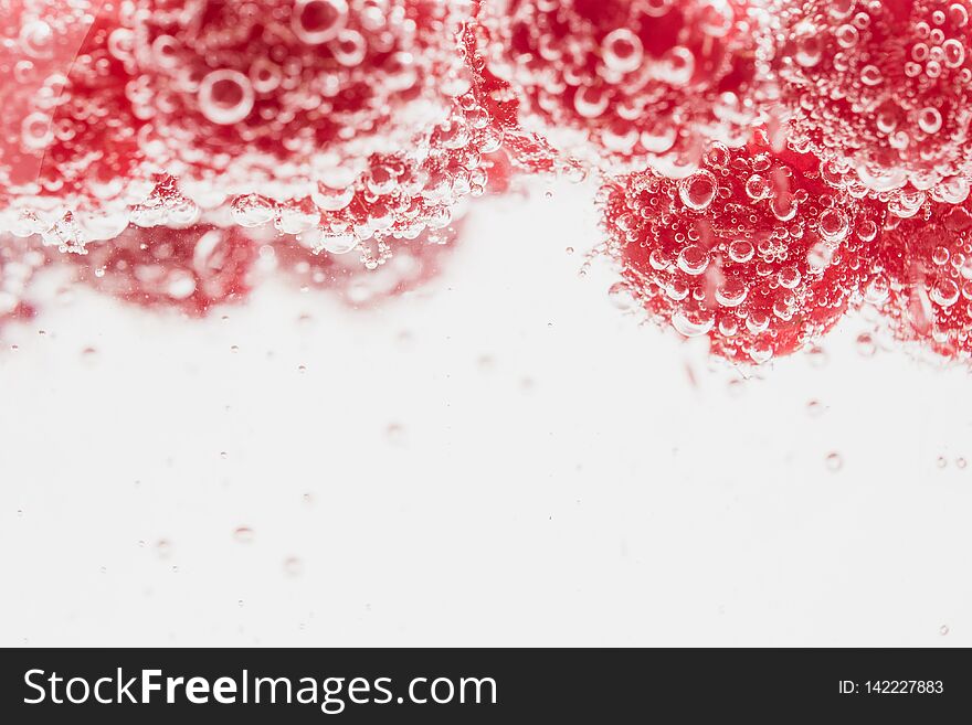 Fresh raspberries in water wiht air bubbles. Close-up photo.