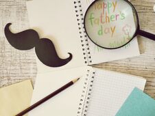 Father`s Tools, Black Paper Mustache, Magnifying Glass, Pencils And A Greeting Inscription In A Notebook On A Light Wooden Table Stock Image