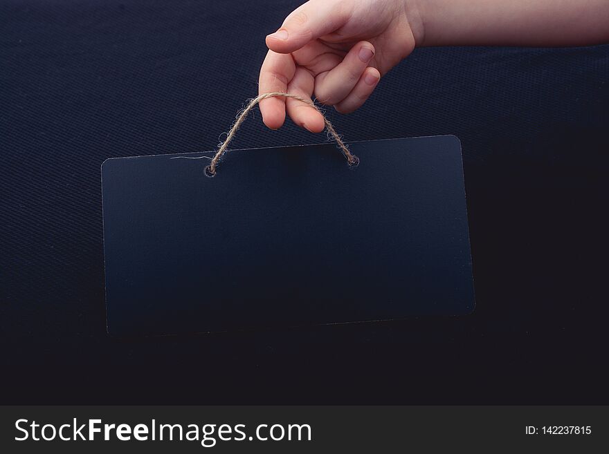 Rectangular shaped black notice board in hand on black background