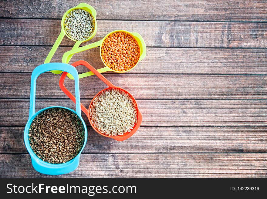 Set of different cereals in multi-colored containers, Oatmeal buckwheat, barley and rice, space for text