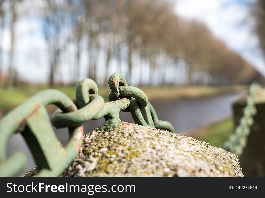 Along the river stand that iron chain on a concrete pole. Along the river stand that iron chain on a concrete pole