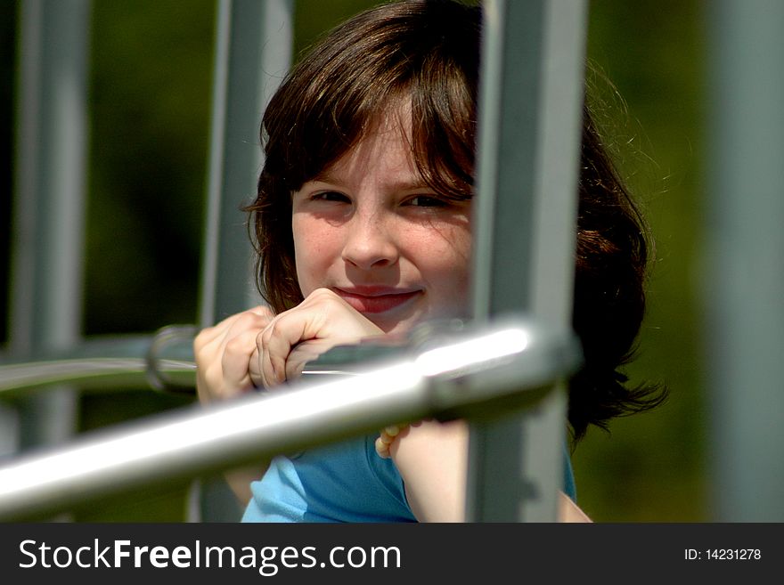 A young girl looks from behind the bars of play equipment. A young girl looks from behind the bars of play equipment