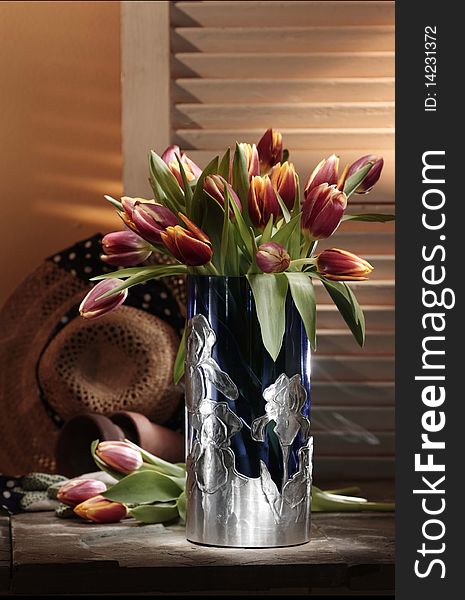 Pink tulip flowers in a metal vase in home setting. Pink tulip flowers in a metal vase in home setting
