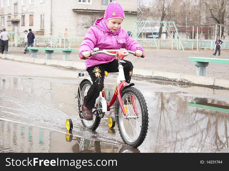 A girl goes through a puddle on a bicycle. A girl goes through a puddle on a bicycle.