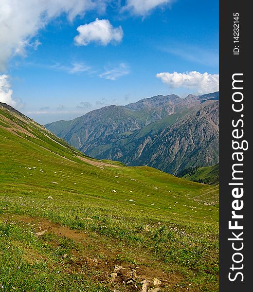 Summer mountains at Shymbulak Ski resort near Almaty, Kazakhstan, with green grass and blue sky