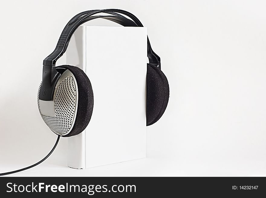 Concept of audiobook - headphones put on hardcover book on white background