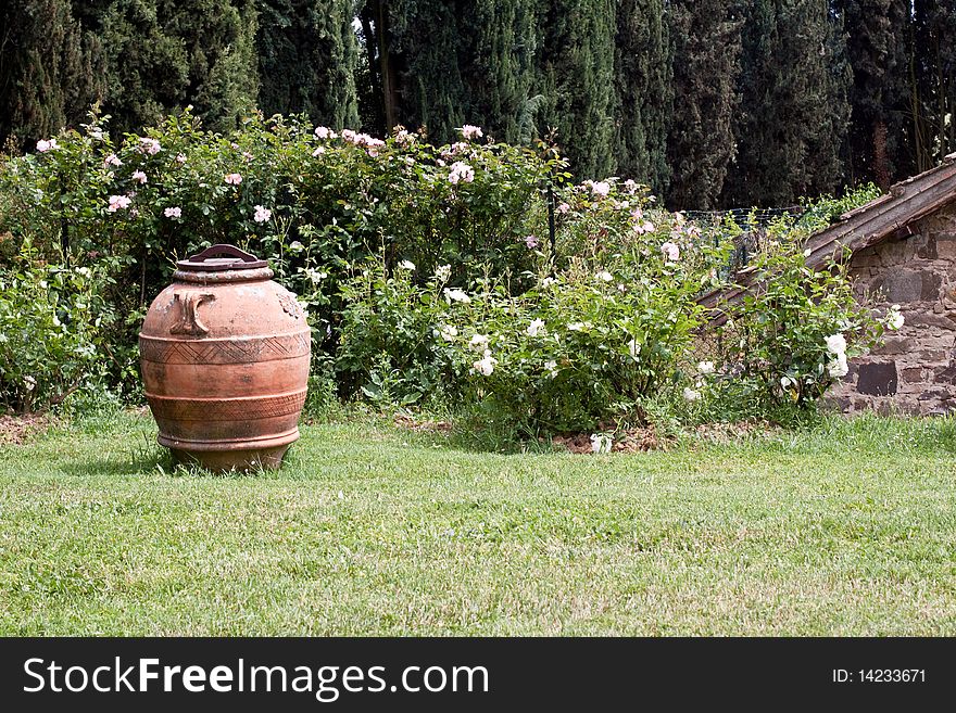 Big brown vase on green grass near flowers. Big brown vase on green grass near flowers