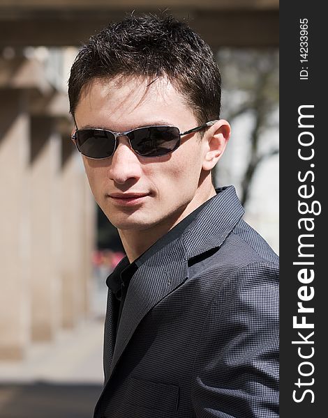 Young confident businessman in black sunglasses and grey jacket. Young confident businessman in black sunglasses and grey jacket