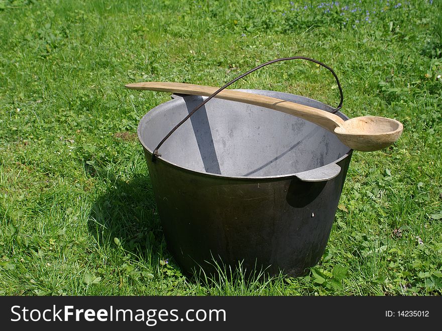 Kettle and wooden spoon in a grass