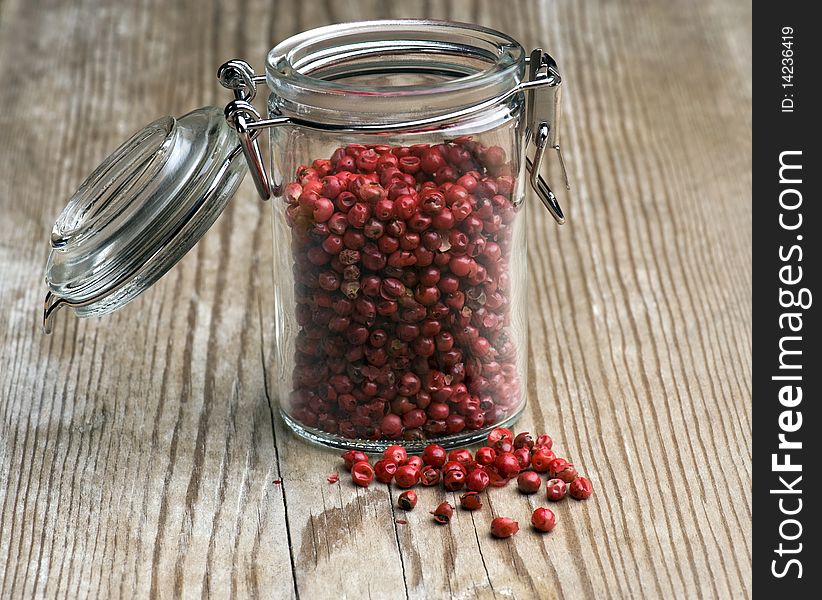 Pink Peppercorns In A Spice Jar Stood On An Old Kitchen Table