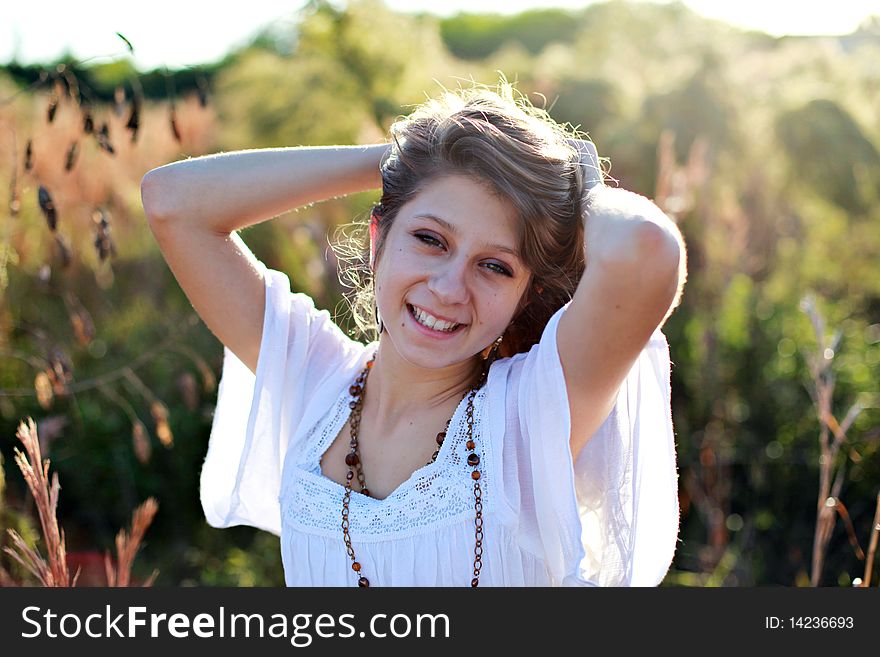 Casual portrait of a beautiful smiling girl with her arms above her head outdoors in spring or summer time. Casual portrait of a beautiful smiling girl with her arms above her head outdoors in spring or summer time.