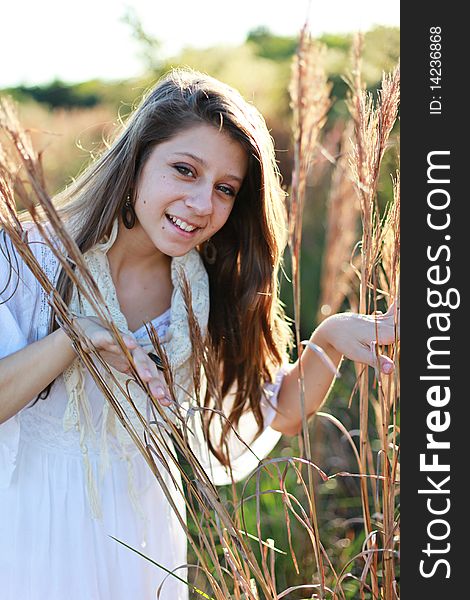 Casual portrait of a beautiful smiling girl holding wheat grasses outdoors in spring or summer time. Casual portrait of a beautiful smiling girl holding wheat grasses outdoors in spring or summer time.