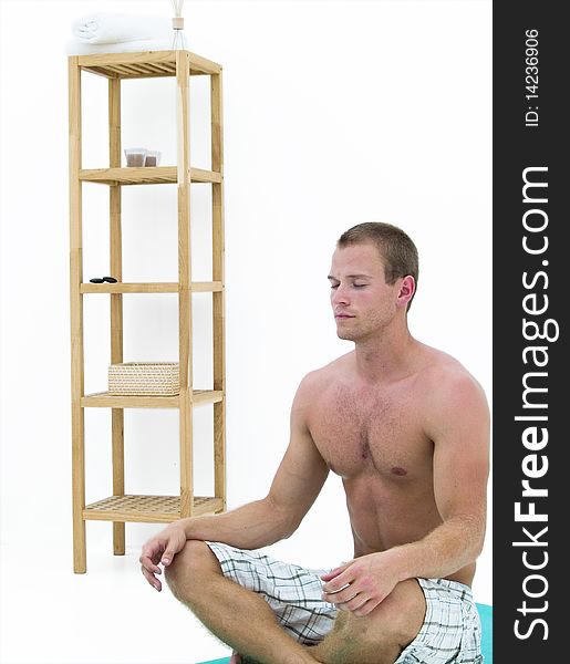 Handsome man relaxing and sitting on a green mat meditating. Handsome man relaxing and sitting on a green mat meditating