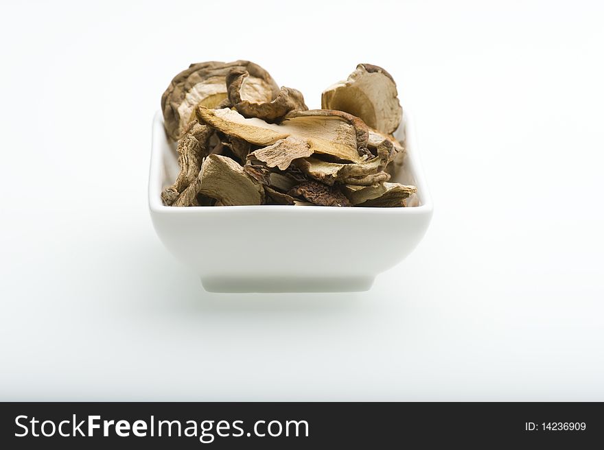 A White Dish Full Of Dried Porcini Mushrooms on A White Background