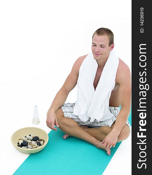 Handsome man relaxing and sitting on a green mat meditating. Handsome man relaxing and sitting on a green mat meditating