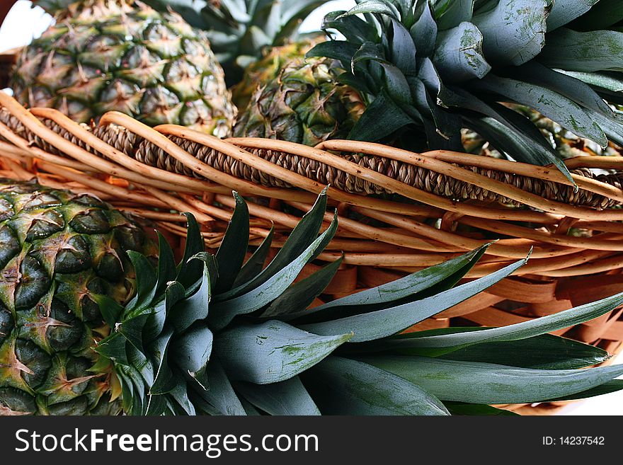 The crop of pineapples is collected in a wattled basket, a background white. The crop of pineapples is collected in a wattled basket, a background white.