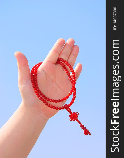 Red prayer beads in sets of fingers. Against the background of blue sky. Red prayer beads in sets of fingers. Against the background of blue sky.