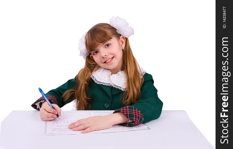 Portrait of a sweet little girl at her classroom, writing an exam. A happy schoolgirl doing her homework. Young student writing.