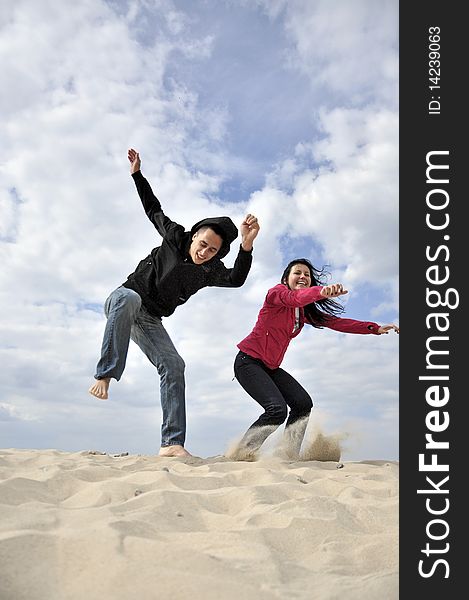 An image showing young girl and boy jumping on the beach. An image showing young girl and boy jumping on the beach