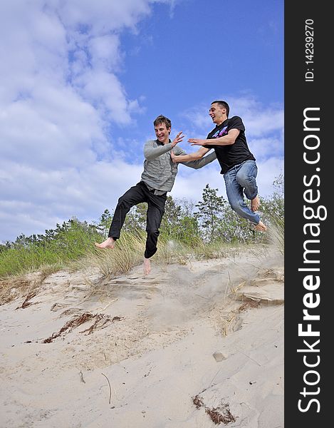 An image showing young boys jumping on the beach. An image showing young boys jumping on the beach