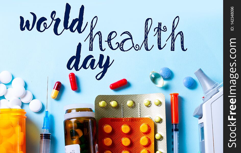 Healthcare concept - pills and medical instruments top view close up border on blue with world health day words. Healthcare concept - pills and medical instruments top view close up border on blue with world health day words