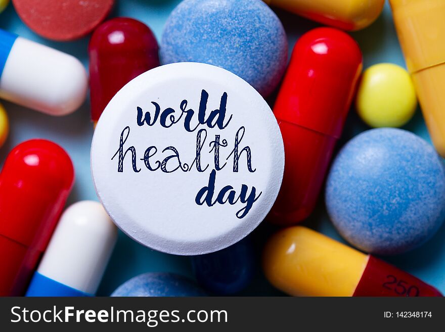 Pile of colorful medical pills close up with world health day words. Pile of colorful medical pills close up with world health day words