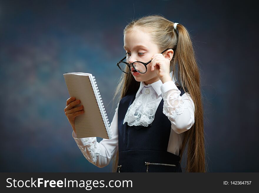 Schoolgirl Wear Glasses Uniform Look at Notebook. Camera Shot on Dark Background. Pensive Little Child with Writing Pad. Clever Elementary School Scholar Study, get Knowledge, do Homework