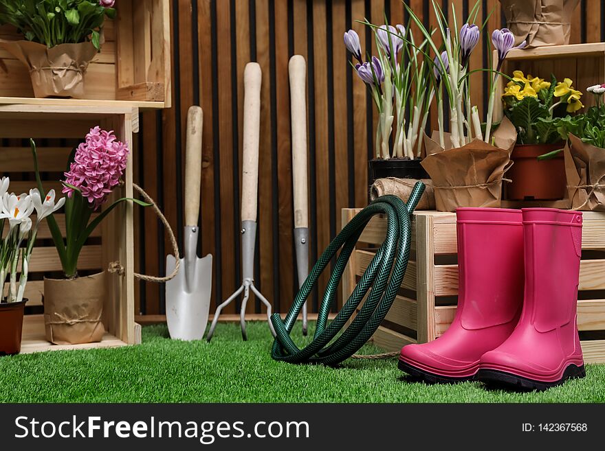 Composition with different gardening tools on artificial grass at wooden wall