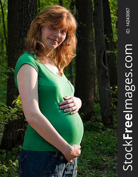 Happy young pregnant woman holding her hands on her tummy