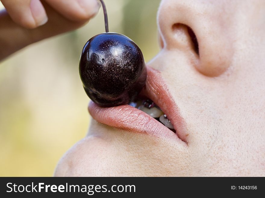 Close up view of a woman trying to eat a cherry. Close up view of a woman trying to eat a cherry.