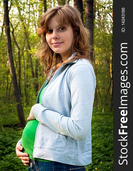 Young pregnant woman holding her hands on her tummy