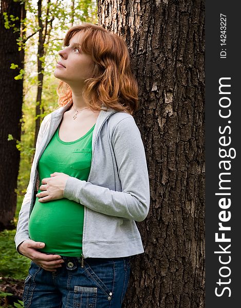 Happy young pregnant woman holding her hands on her tummy