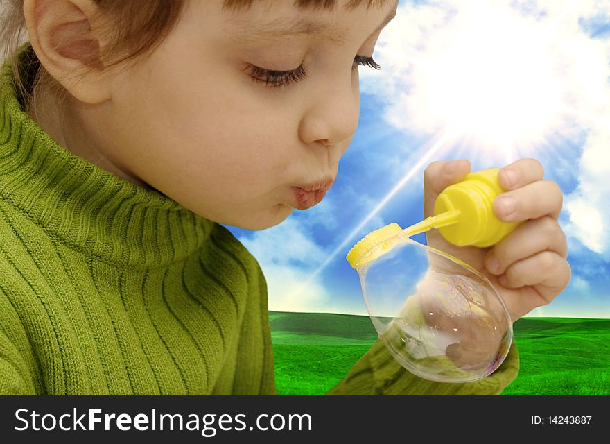 The girl inflating soap bubbles on a meadow